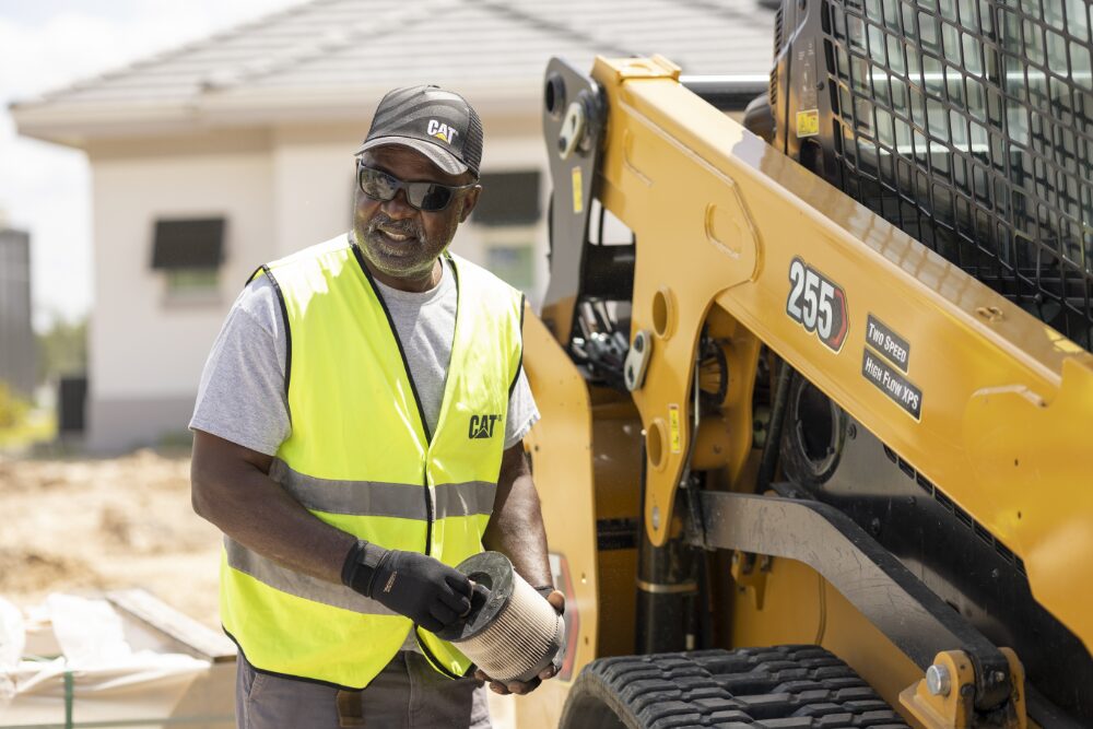 man standing beside a Cat 255