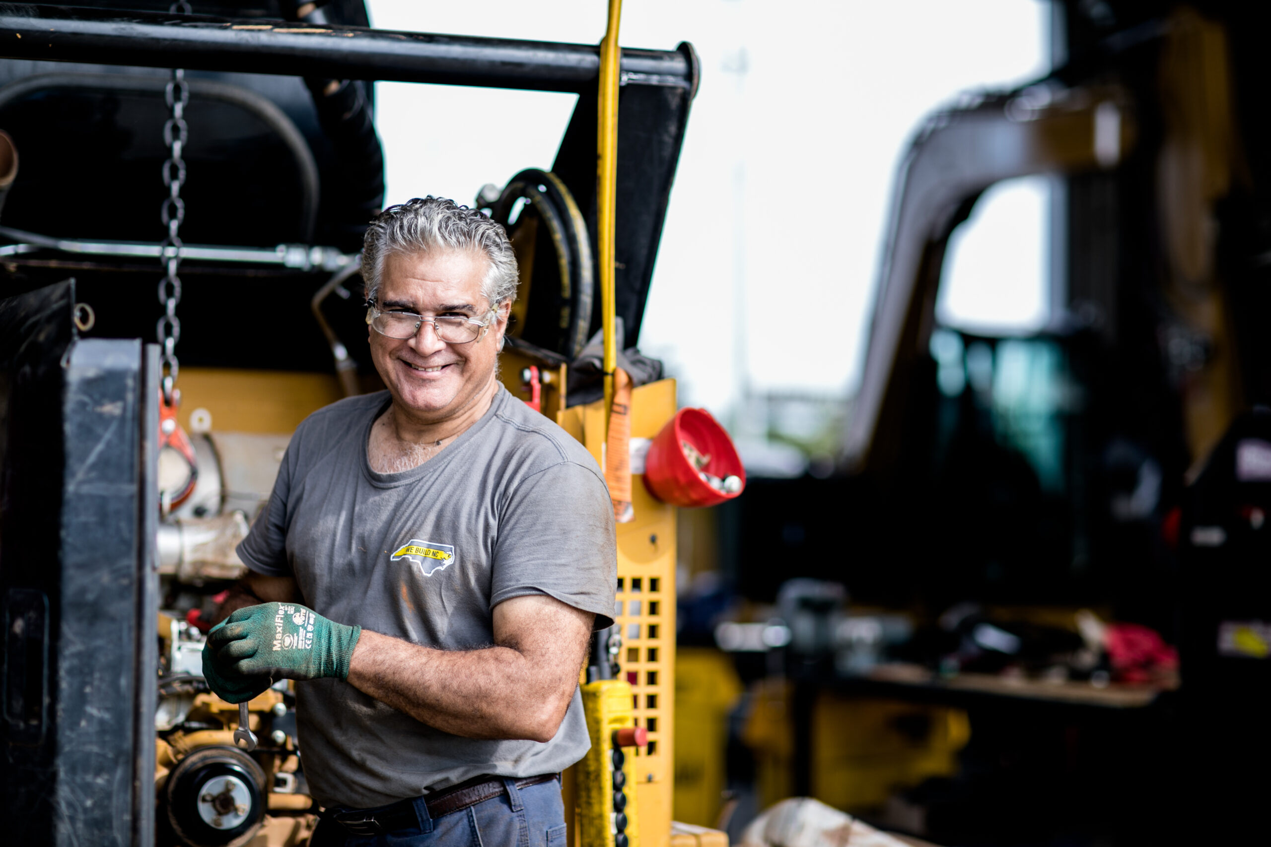 technician with grey hair and glasses smiling as he works